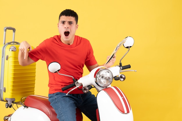 Front view bewildered young man on moped holding map