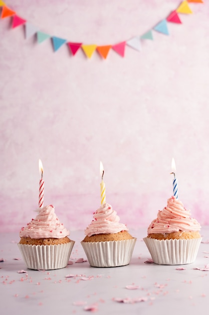 Вид спереди на день рождения кексы с гирляндой и зажженными свечами