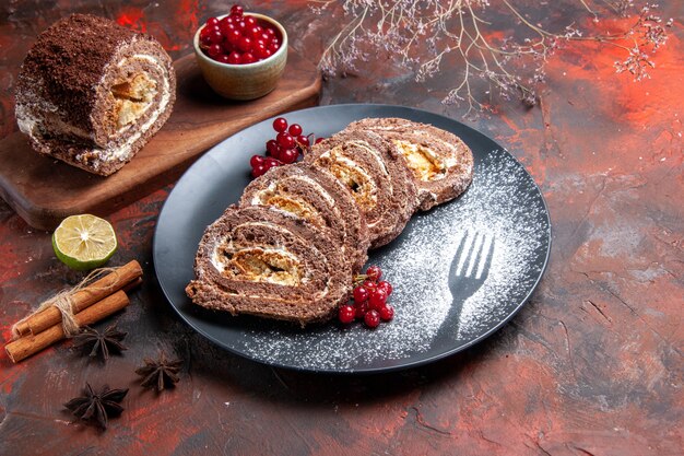 Front view of biscuit rolls with red fruits on dark surface