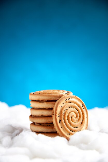 Печенье, вид спереди, сложенное друг на друга на синем фоне