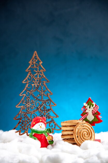 파란색 배경에 서로 다른 크리스마스 장식품 위에 쌓인 전면 보기 비스킷