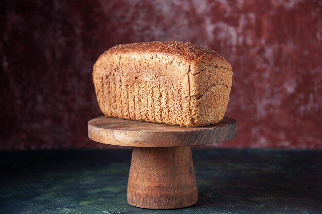 Front view of black bread slices on cutting board on mixed colors distressed background with free space