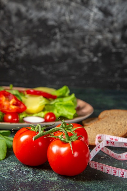 Front view of black bread slices fresh tomatoes with stem and meters green bundle on dark colors surface