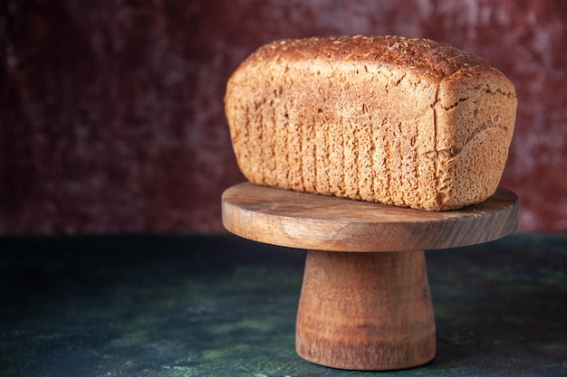 Front view of black bread slices on wooden board on mixed colors distressed background with free space