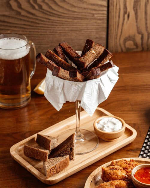 Вид спереди черный хлеб с соусом и курицей на коричневом деревянном столе еда хлебная булочка закуска