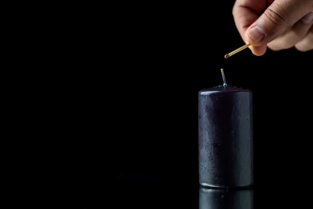 Front view of black candle on a dark surface