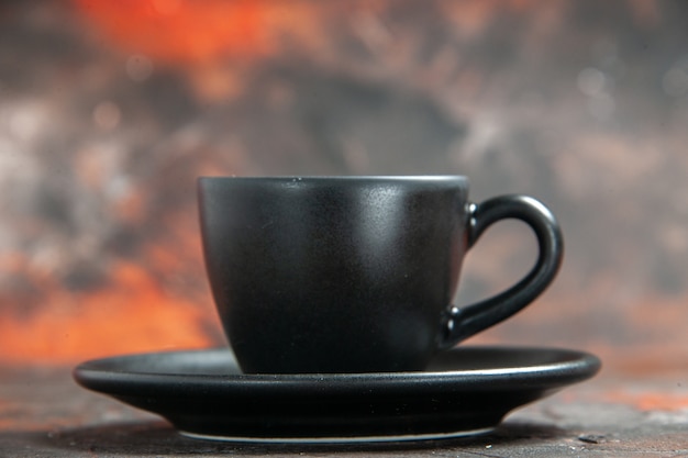 暗い隔離されたテーブルの正面図の黒いカップとソーサー