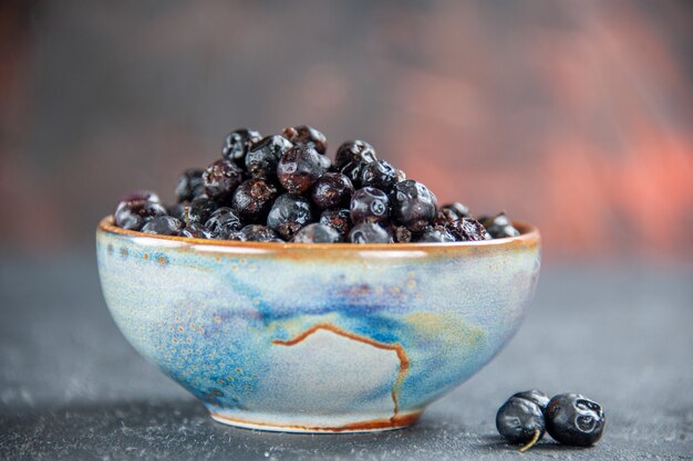 Front view black currant in bowl on dark surface