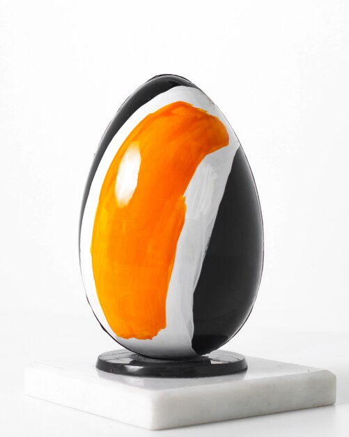 Front view black egg white-yellow designed on the white desk