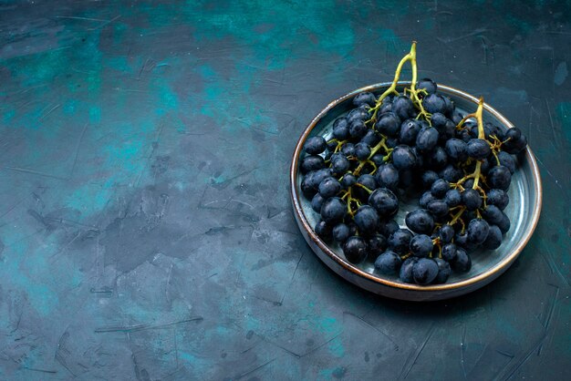 Вид спереди черный виноград внутри подноса на темно-синем столе