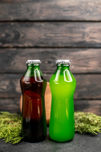 Free photo front view black green lemonade in bottles wood board