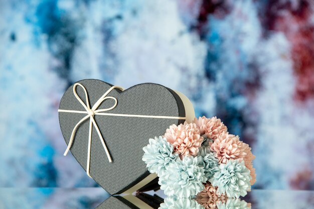 Front view of black heart box and colored flowers on abstract background