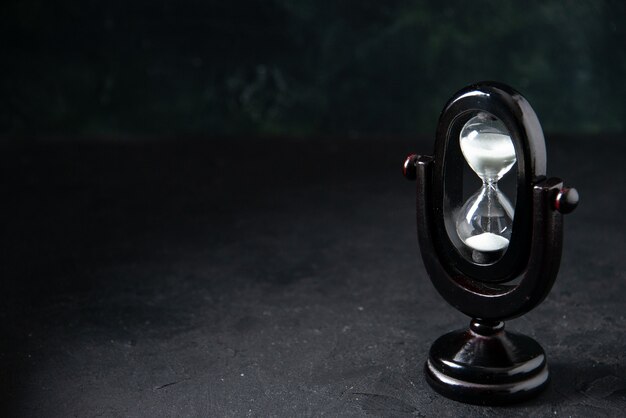 Front view of black hourglass on dark surface