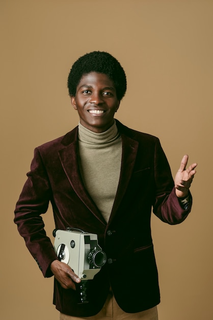 Front view black man holding old video camera