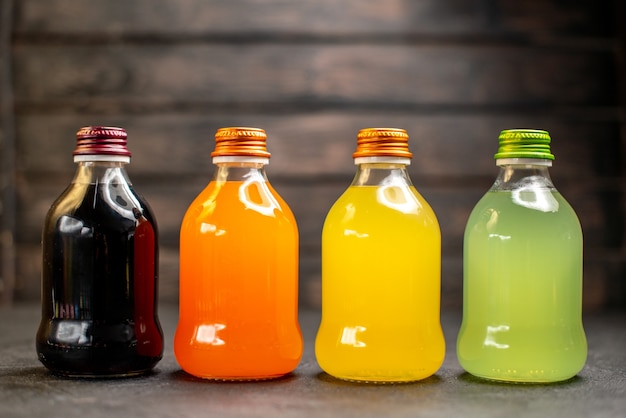 Вид спереди черный оранжевый желтый и зеленый фруктовый сок в бутылках