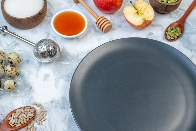 Front view of black plate and ingredients for the healthy food set on ice background