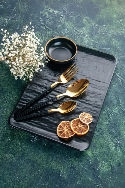 front view black plate with golden cutlery on dark background