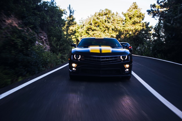 Front view of a black sport car with two yellow stripes on it.