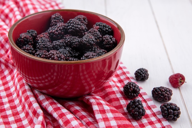 Front view of blackberry in a red bowl on a red checkered towel on a white surface