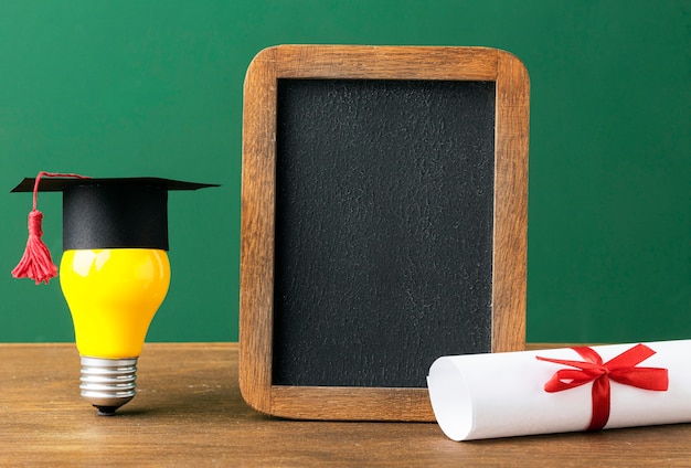 Front view of blackboard with lightbulb and academic cap