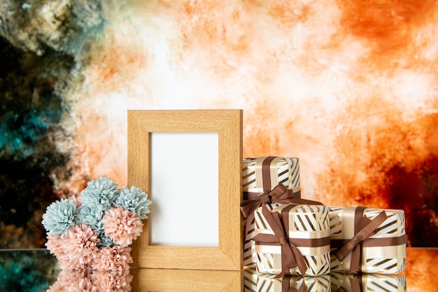 Free photo front view of blank picture frame holiday presents flowers on abstract background