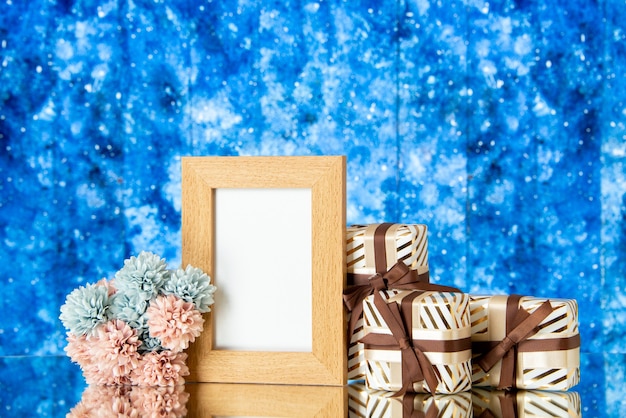 Бесплатное фото Вид спереди пустая рамка для фотографий праздник представляет цветы на синем абстрактном фоне