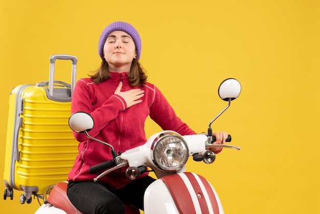 Front view blessed young woman on moped putting hand on her chest