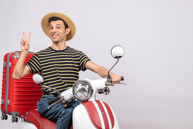 오토바이 몸짓 승리 기호에 밀짚 모자와 함께 행복 한 젊은 남자의 전면보기