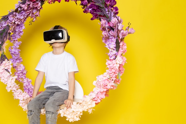 A front view blonde boy playing vr on the flower made stand on the yellow desk