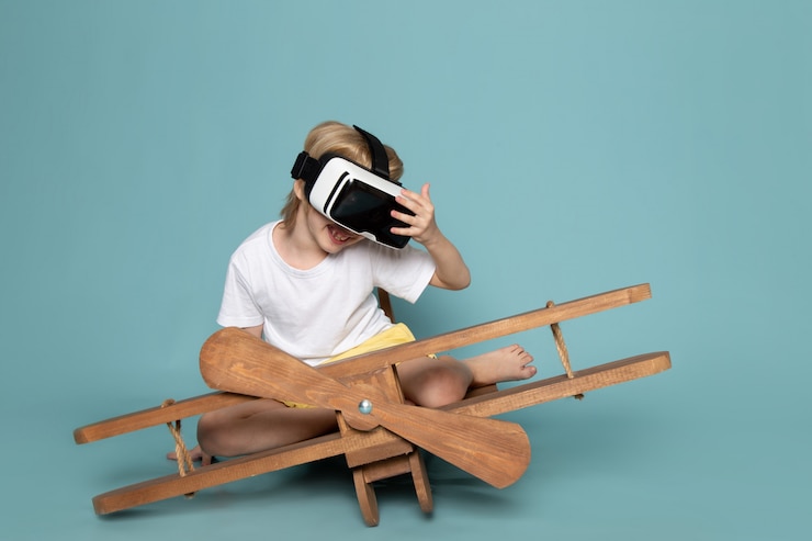 Free Photo front view blonde boy playing vr goggles in white t-shirt on the blue desk