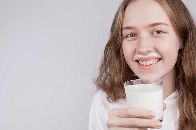Front view blonde girl holding a glass of milk