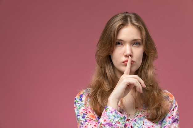 Front view blonde lady showing silence gesture and staring at straight