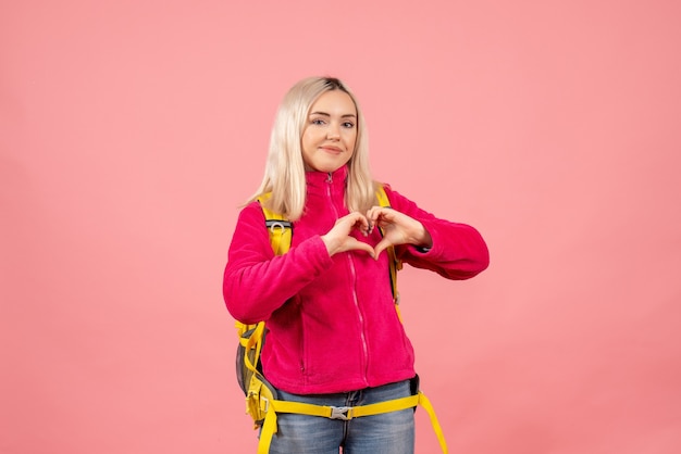 Front view blonde traveler woman in casual clothes making heart sign