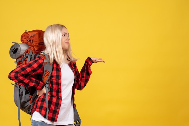 Front view blonde traveler woman with her backpack putting hand on a waist