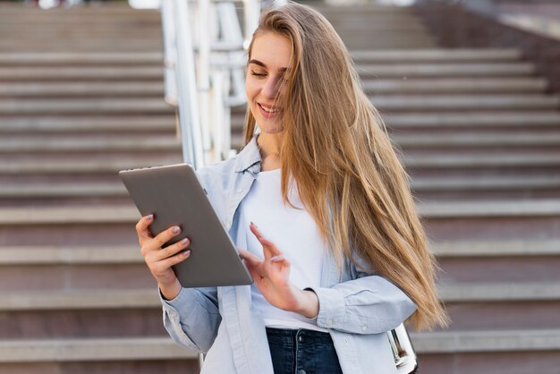 Front view blonde woman using a tablet