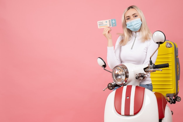 Foto gratuita giovane signora bionda di vista frontale sul ciclomotore con il biglietto giallo della tenuta della valigia