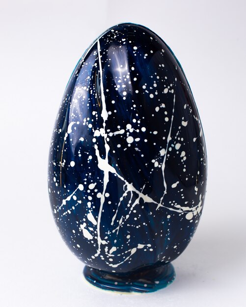 Front view blue chocolate egg in white speckled on stand