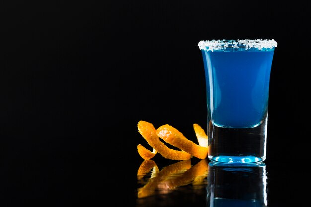 Вид спереди голубой коктейль в рюмку с апельсиновой коркой