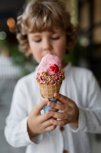 Вид спереди размытый ребенок держит рожок мороженого