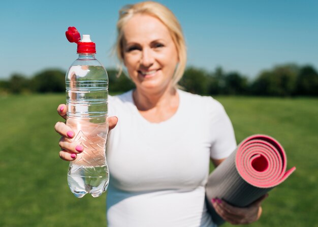 Front view blurry woman holding water bottle