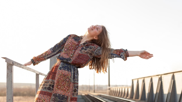 Free photo front view of bohemian woman posing by the train tracks