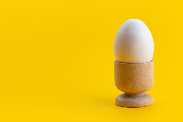 A front view boiled egg white, whole and inside little stand on yellow, food meal color