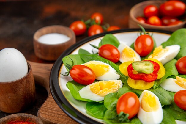 Вид спереди вареные яйца с приправами и помидорами на темном завтраке, гамбургере, хлебе, яйце, обеде