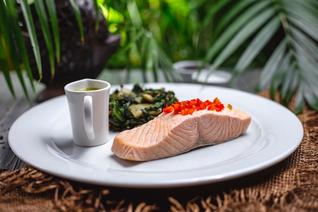 Front view boiled red fish with stew greens and sauce on a plate