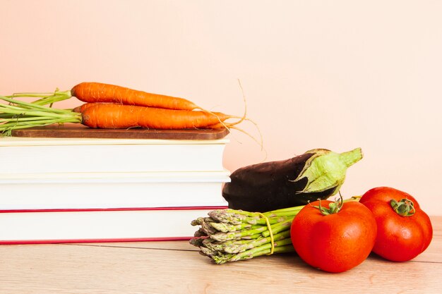 Front view of books and vegetables with plain background