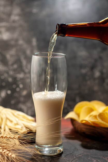 Front view bottle of bear pouring into the glass on light background