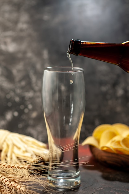 Front view bottle of bear pouring into the glass on light background