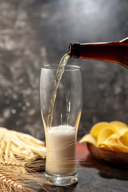 Front view bottle of bear pouring into the glass on light background