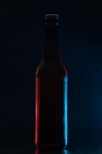 짙은 파란색 배경에 맥주 한 병의 전면 뷰 음료 색상 물 소다 유리 어둠 사진