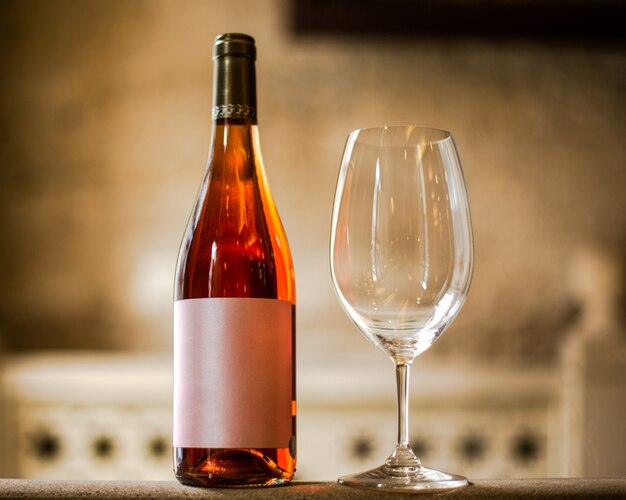 A front view bottle of wine along with glass on the light wall